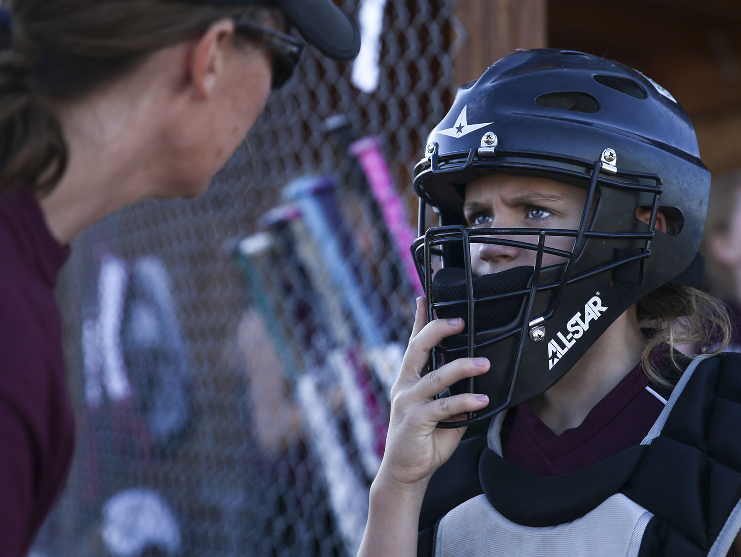 Emery Cox checks the positioning of the catchers mask with her coach